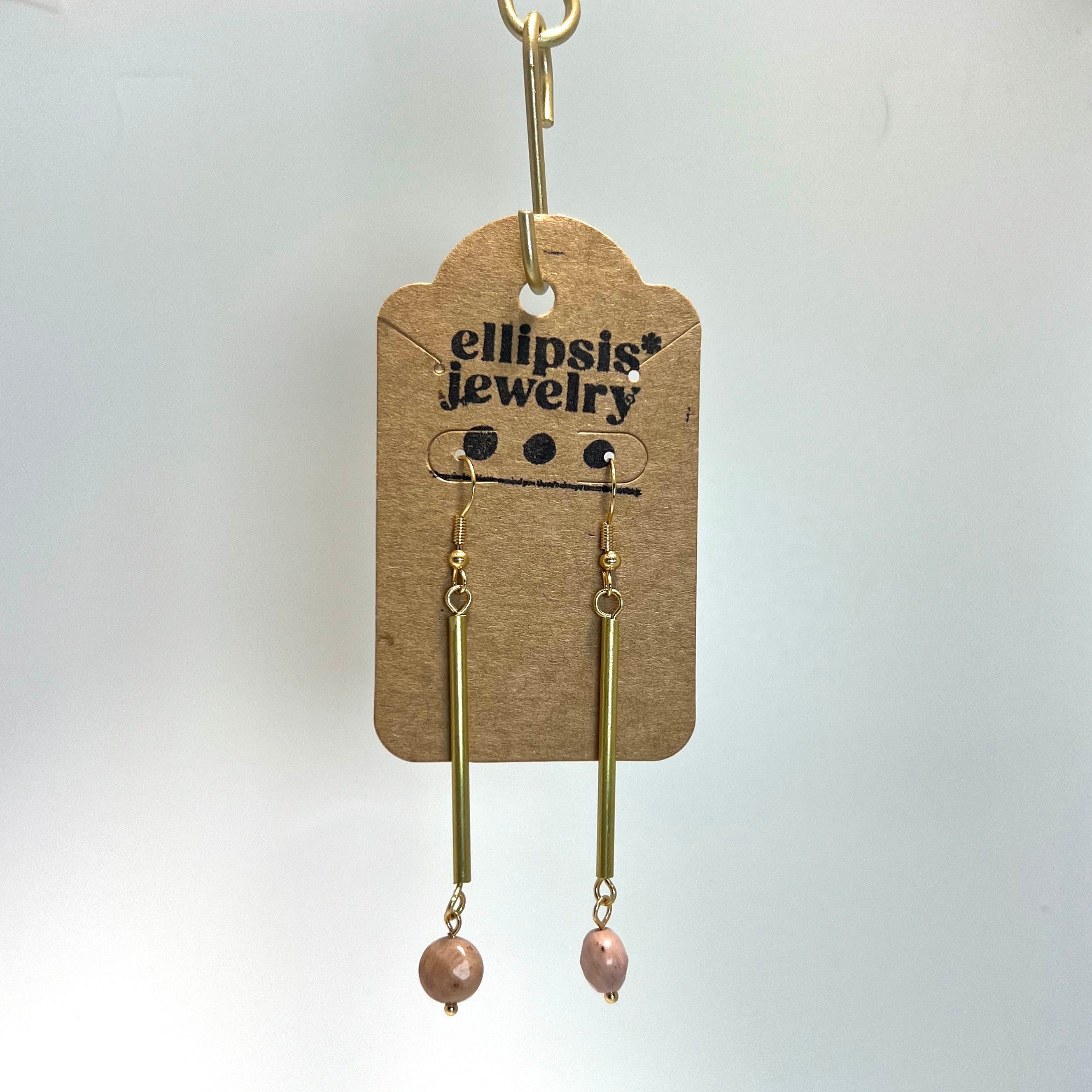 Brass earrings with pink beads on a 'ellipsis jewelry' branded card against a white background